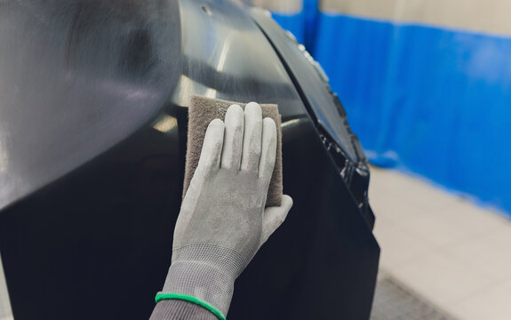 Auto mechanic preparing the car for paint job by applying polish with the power buffer machine