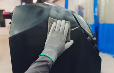 Auto mechanic preparing the car for paint job by applying polish with the power buffer machine