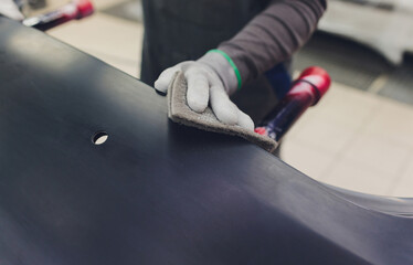 Auto mechanic preparing the car for paint job by applying polish with the power buffer machine