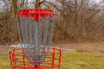 Red disc golf goal, net, pole hole, entrapment basket on a raw winter day.  