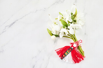 A bouquet of snowdrops flowers and a red-white martenitsa, a symbol of the holiday on March 1, Martisor, Baba Marta.