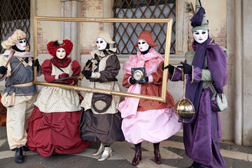 Venice, Italy - February 2022 - carnival masks are photographed with tourists in San Marco square