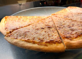 Four slices of New York style cheese pizza for sale by the slice