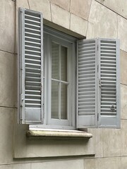 Window on a stone building with old, gray, open shutters