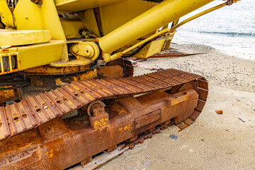 Detail of an old and rusty excavator abandoned on the beach - 734278247