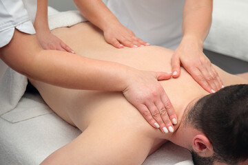 Fototapeta na wymiar Four hands massage of man back, spa salon treatment