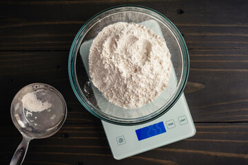 Weighing a Large Bowl of All-Purpose Flour on a Kitchen Scale: Glass mixing bowl of flour on a digital scale with a measuring cup on the side