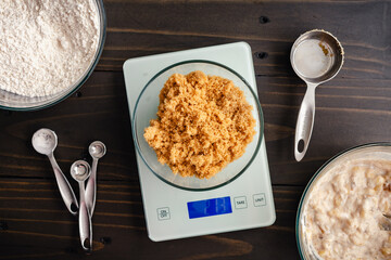Weighing Light Brown Sugar on a Kitchen Scale: Brown sugar weighed on a digital scale with wet and...