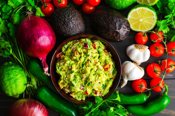 Bowl of Guacamole Surrounded by Fresh Ingredients: Guacamole with Hass avocados, jalapeno peppers, cherry tomatoes, and other ingredients