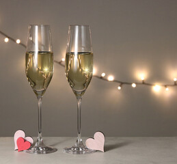 Two champagne glasses with wine with heart decoration in a romantically lit environment - celebration of Valentine's Day or wedding