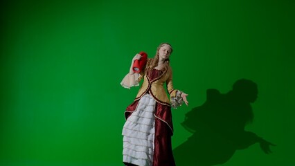 Woman in ancient outfit on the chroma key green screen. Female in renaissance style dress holding music speaker singing song and dancing.
