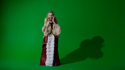 Woman in ancient outfit on the chroma key green screen background. Female in renaissance style dress looking at the camera, amazed surprised face.