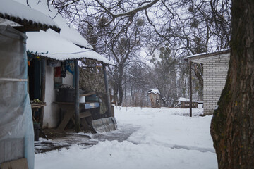 Kyiv, Ukraine - February 10, 2024. A snowy yard in my grandmother's village. icicles hang from the roof. snow on the roof of the house. closed shell on the street with snow. gloomy weather, gray sky