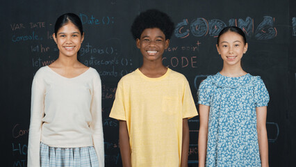 Multicultural smart people smiling at camera at blackboard with prompt or code. Group of diverse...