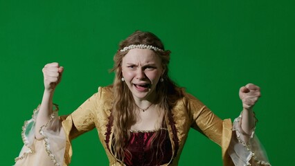Woman in ancient outfit on the chroma key green screen background. Female in renaissance style dress posing looking at the camera angry shouting.