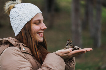 Woman With Braces Holding Pine Cone in Hands Outdoors