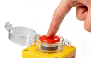 Finger pressing down on a large red yellow button with a clear plastic lid isolated on white background man pressing an emergency industrial machinery stop button, closeup, one person, safety protocol