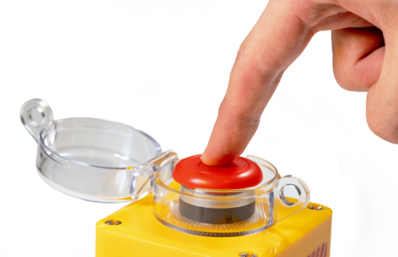 Finger pressing down on a large red yellow button with a clear plastic lid isolated on white background man pressing an emergency industrial machinery stop button, closeup, one person, safety protocol