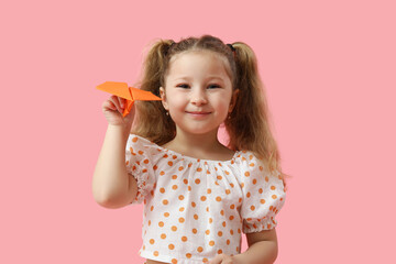 Cute little girl with paper plane on pink background