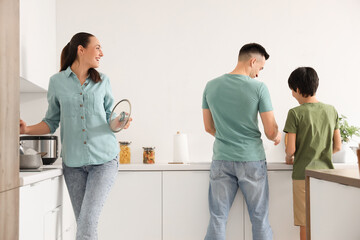 Little boy with his parents washing dishes in kitchen