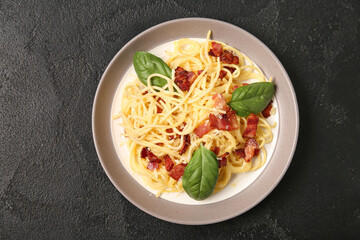 Plate with tasty pasta carbonara on black background