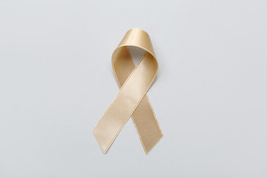 Beige ribbon on light background. Uterine cancer awareness concept