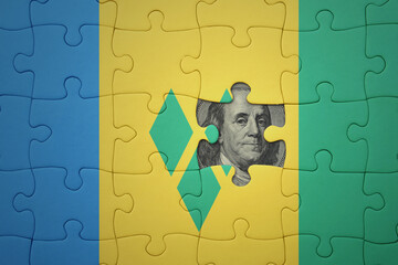 puzzle with the national flag of saint vincent and the grenadines and usa dollar banknote. finance concept