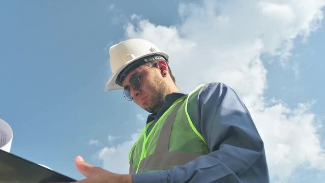 Latin construction worker man looking documents in construction site in sunny day