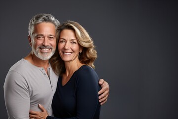 smiling middle aged couple on dark grey isolated background