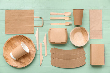 Eco tableware with paper bag on green wooden background