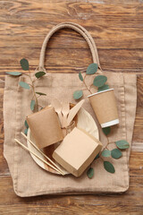 Eco tableware with plant leaves and bag on brown wooden background