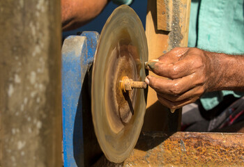 Close-up on a man's hand sharpening a part with a machine. Suitable for handicrafts and traditional professions in Sri Lanka