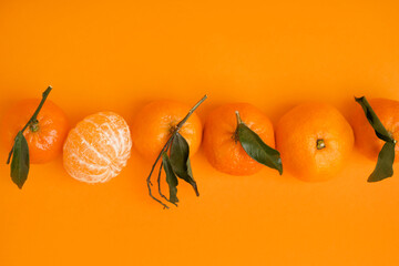 Tasty tangerines with leaves on orange background
