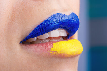 Close up of beautiful and plump female lips painted in blue and yellow. Lips of woman painted in Ukrainian flag colors.