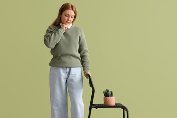 Mature woman with hemorrhoids and cactus on chair against green background