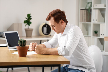 Young businessman sitting on toilet bowl in office. Hemorrhoids concept