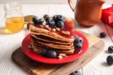 Plate with tasty pancakes in shape of heart, blueberry and jam on light wooden background, closeup. Valentine's Day celebration