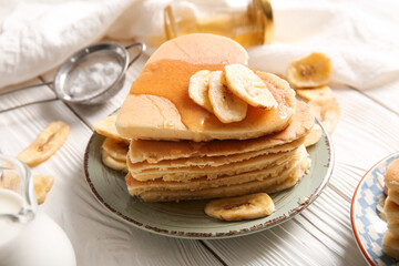Plate with tasty pancakes in shape of heart and dried banana on light wooden background, closeup. Valentine's Day celebration