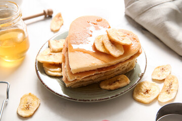 Plate with tasty pancakes in shape of heart and dried banana on light background, closeup. Valentine's Day celebration