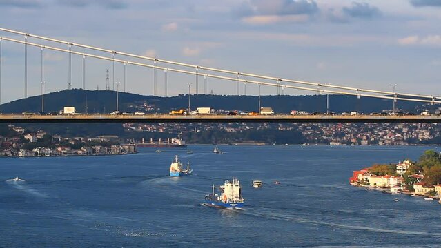 Heavy bus and truck traffic on suspension bridge FSM and cargo ships sailing slowly towards Black Sea. Istanbul, Turkey. Aerial view of Bosphorus with a static camera and tele lens. 
