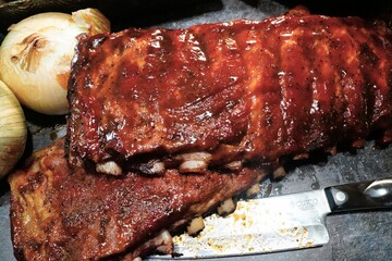 smoked barbecue ribs with onions and a knife ready for dinner or summertime BBQ