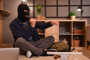 Male thief with flashlight stealing jewels in room at night