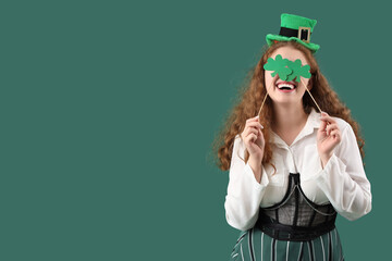 Young woman with paper clovers on green background. St. Patrick's Day celebration