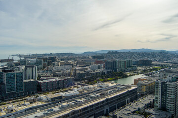 Fototapeta premium aerial shot of office buildings, apartments and retail stores in the city skyline with ocean water and lush green trees and grass in San Francisco California USA