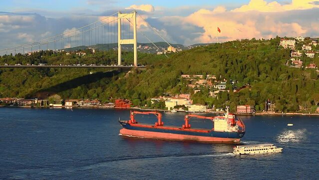 A dry cargo ship underway Bosphorus towards Black Sea during sunset. Kandilli district with luxury mansions has a uniquely beautiful sea view on the coastline. Istanbul, Turkey
