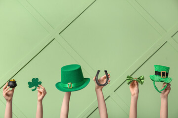 Female hands holding different party decor for St. Patrick's Day celebration on green background