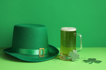 Glass of beer with leprechaun hat and clover on green background. St. Patrick's Day celebration