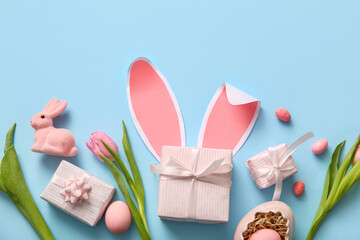 Easter eggs with gift boxes, tulip flowers and bunny on blue background