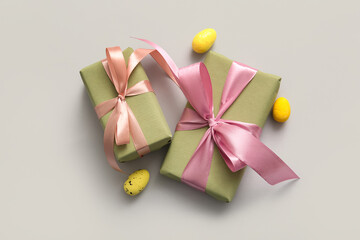 Easter eggs with gift boxes on grey background
