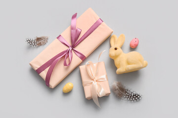 Easter eggs with gift boxes and bunny on grey background